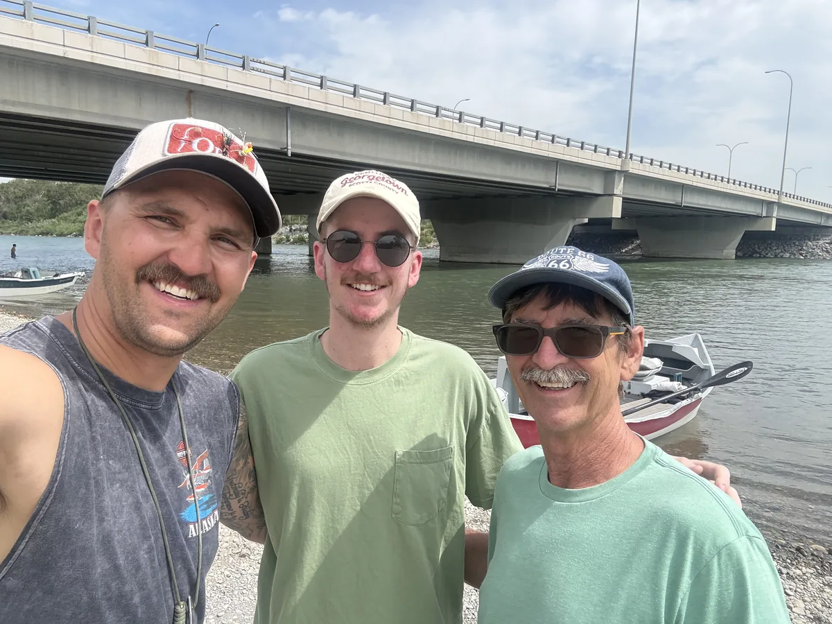 Guide Dan King with two happy clients at the boat launch after a guided Bow River fishing trip, drift boat behind